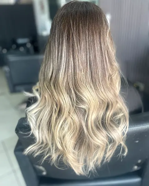 Balayage rubio sobre raíz oscura, en ondas largas