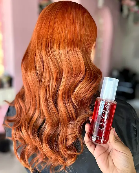 Cabello cobre intenso con un producto Avyna en la mano