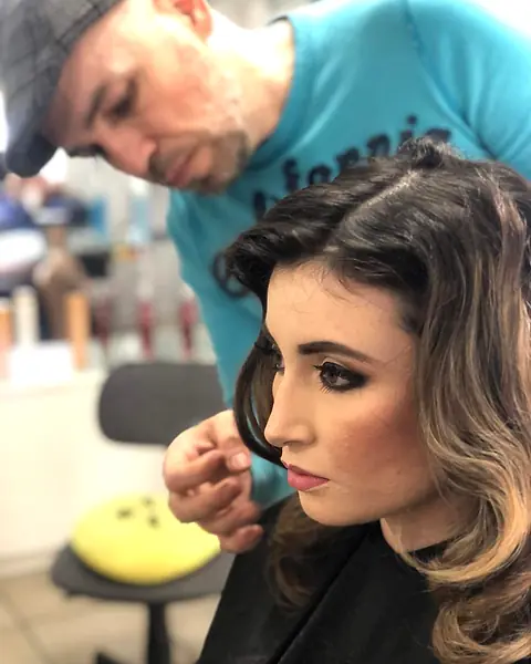Alberto Muñoz terminando el peinado de una clienta maquillada