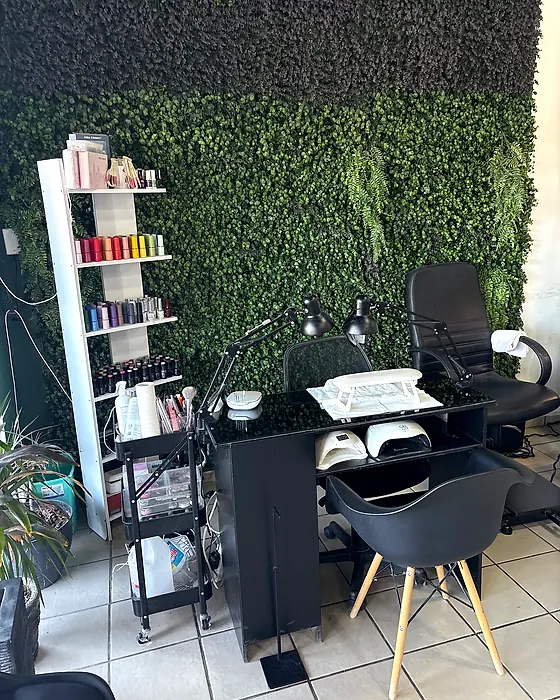 Mesa de uñas del salón junto al muro de plantas
