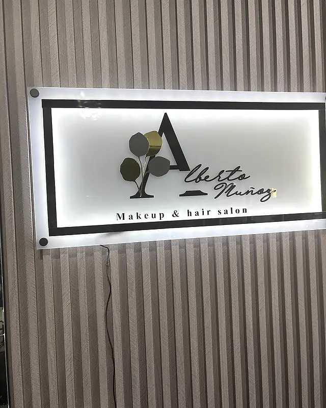 Letrero iluminado con el logo de Alberto Muñoz en el salón
